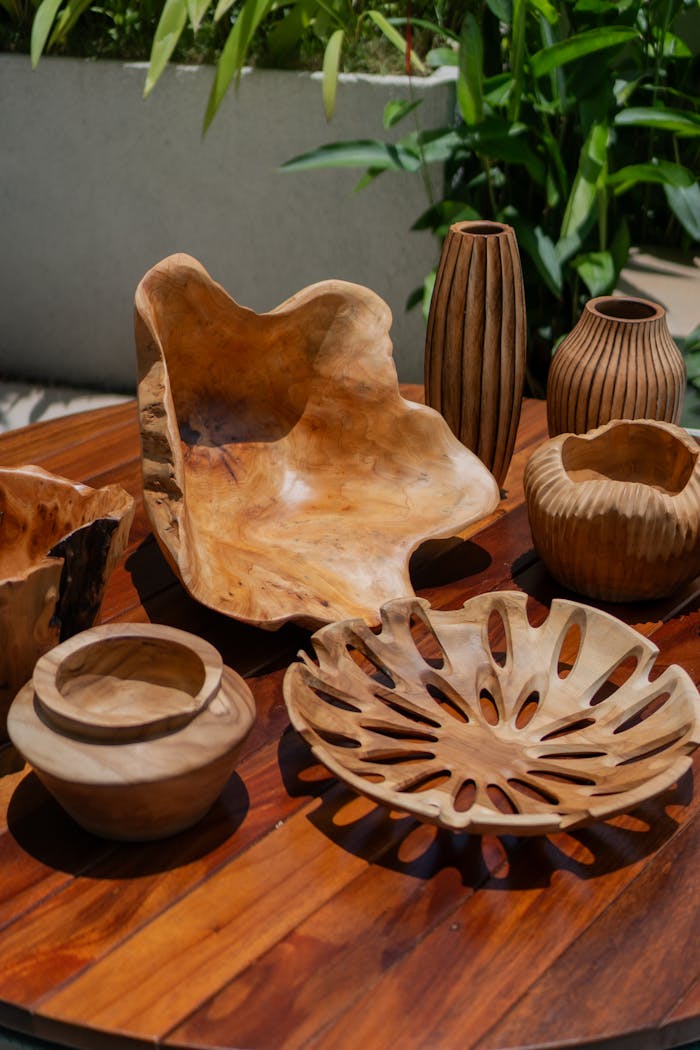 Artistic wooden bowls and vases arranged on a table outdoors, showcasing craftsmanship.