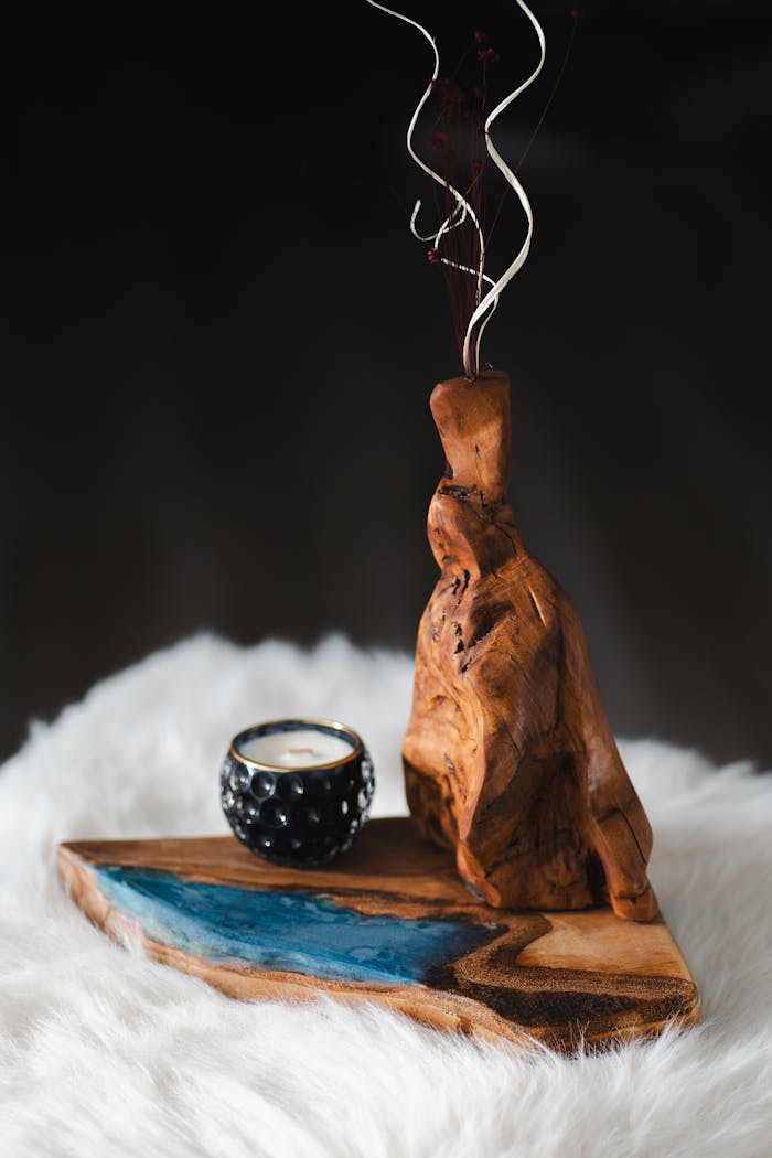 Intricate wooden sculpture and candle on a plush fur surface, perfect for decor.